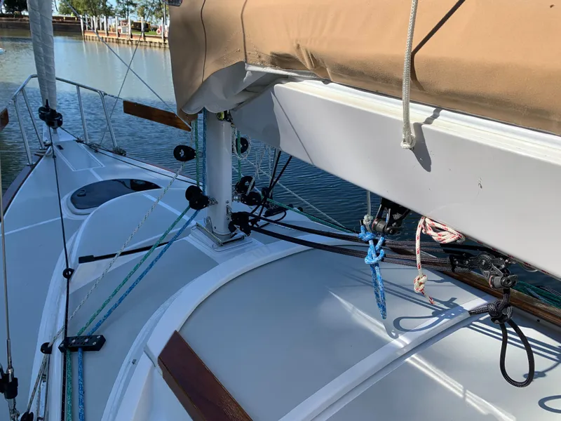 Slide: The Image of 2022 Tartan Fantail sailboat deck with rigging and tan sail cover, docked by calm water. - 9