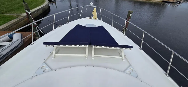 Slide: The Image of 2006 Cruisers Yachts 52 Express deck with blue sun loungers, docked by calm water. - 32