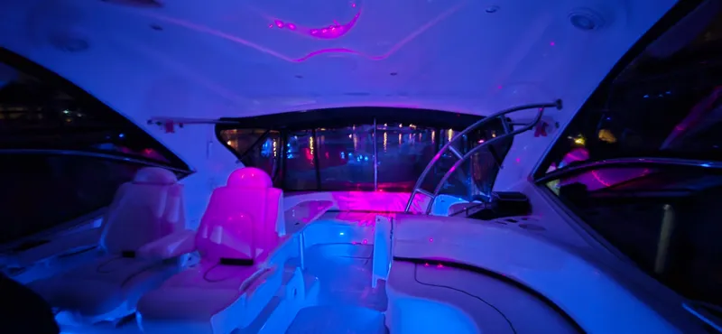 Slide: The Image of Interior of 2006 Cruisers Yachts 52 Express with vibrant blue and pink lighting. - 34
