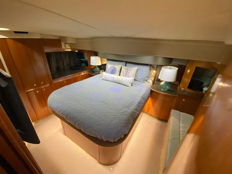 Slide: The Image of Luxurious bedroom in 2006 Cruisers Yachts 52 Express with elegant wood cabinetry. - 56