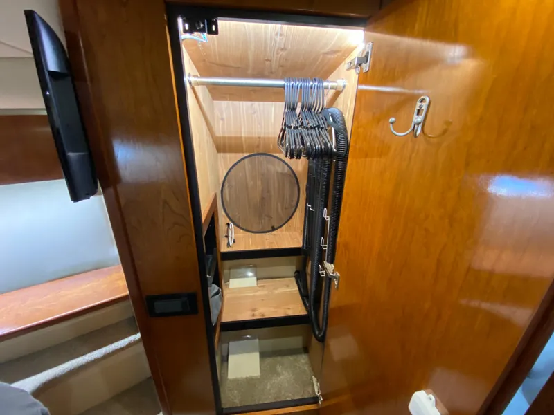 Slide: The Image of Wooden closet interior on 2006 Cruisers Yachts 52 Express, featuring hangers and hooks. - 73