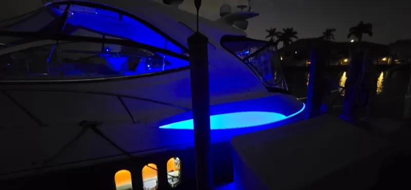 Slide: The Image of 2006 Cruisers Yachts 52 Express with blue LED lights at night, docked by the water. - 9