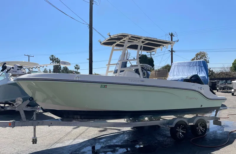 Slide: The Image of 2022 Bayliner Trophy T22CC boat on trailer, parked outdoors under clear sky. - 3