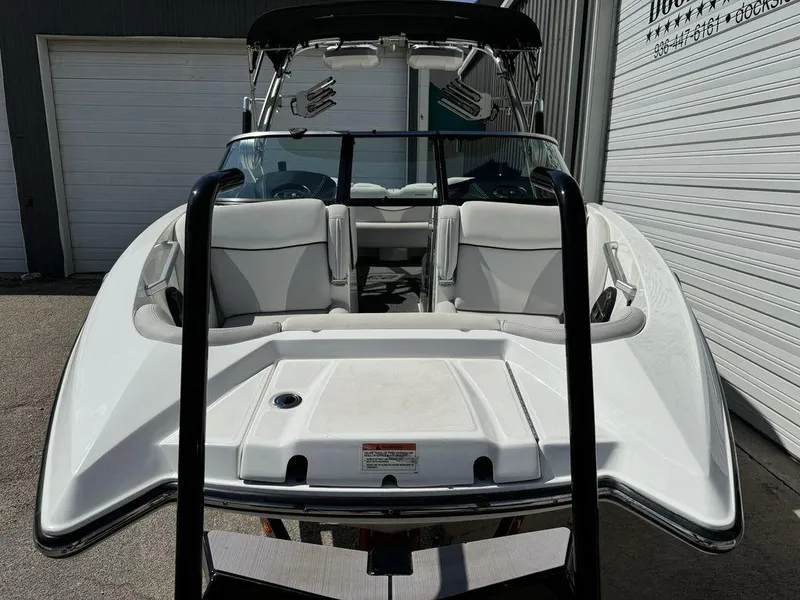 Slide: The Image of 2018 MasterCraft X23 boat, white interior, parked near garage doors. - 2