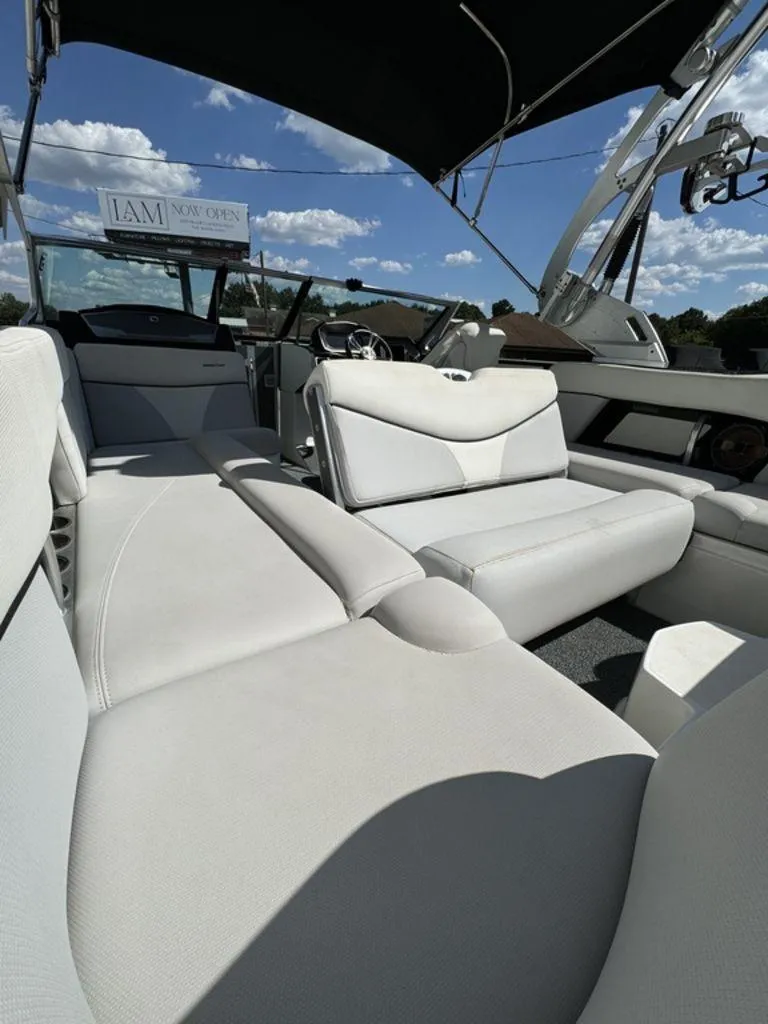Slide: The Image of 2018 MasterCraft X23 boat interior with white seating and canopy under blue sky. - 9