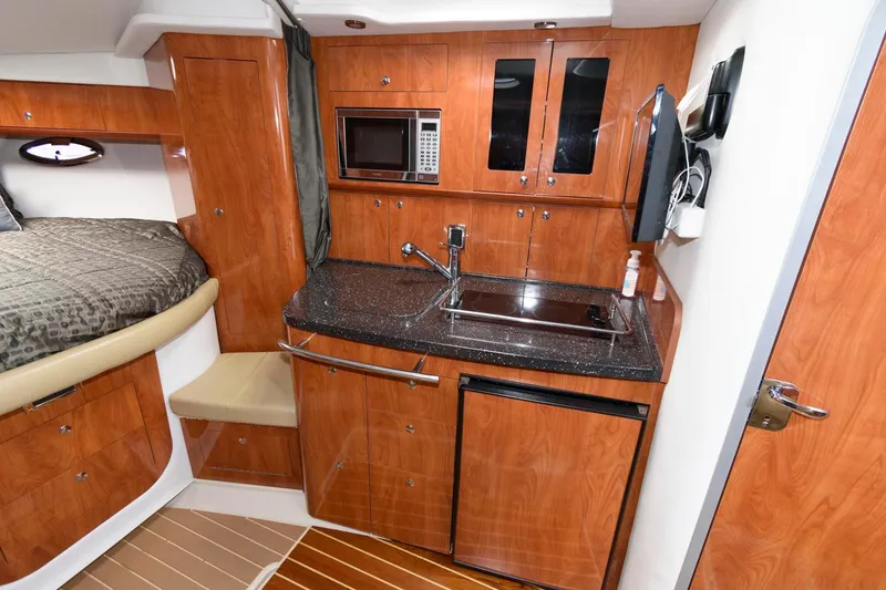 Slide: The Image of 2008 Four Winns V338 yacht interior with kitchenette, featuring wood cabinetry and modern appliances. - 13