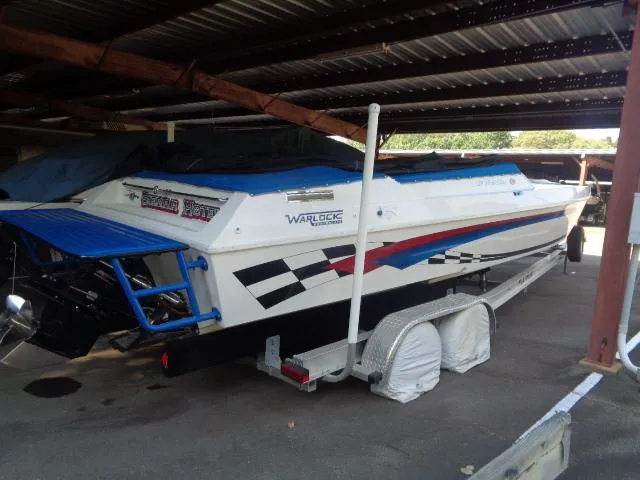 Slide: The Image of 2001 Warlock 29 World Class boat with colorful graphics, parked under a metal shelter. - 17