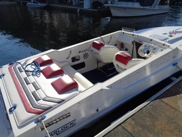 Slide: The Image of 2001 Warlock 29 World Class boat with red and white interior, docked by the water. - 2