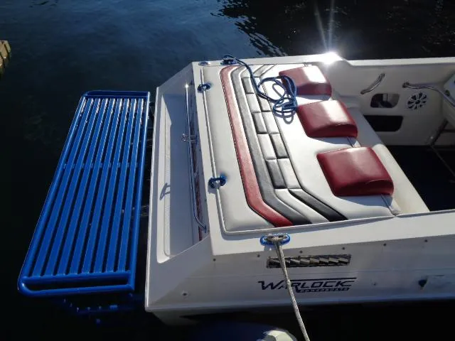 Slide: The Image of 2001 Warlock 29 World Class boat with red and gray seating, docked on water. - 3