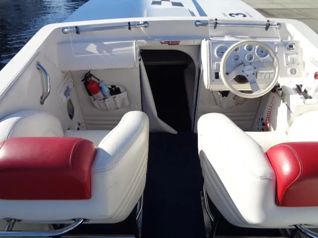 Slide: The Image of 2001 Warlock 29 World Class boat interior with white and red seating, steering wheel, and storage pockets. - 7