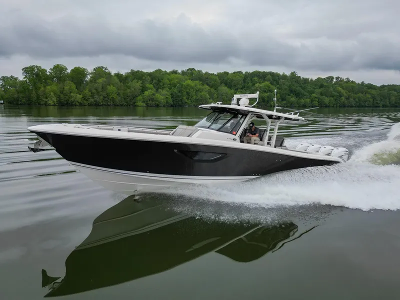 The Image of 2021 Pursuit S 428 Sport boat cruising on a calm lake with lush green trees. - 0