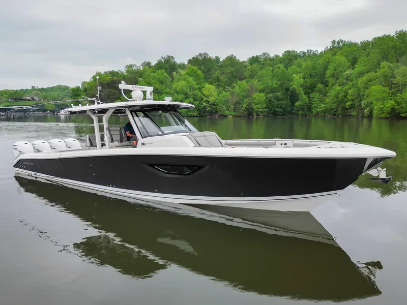 Slide: The Image of 2021 Pursuit S 428 Sport boat on a calm lake with lush green trees. - 2