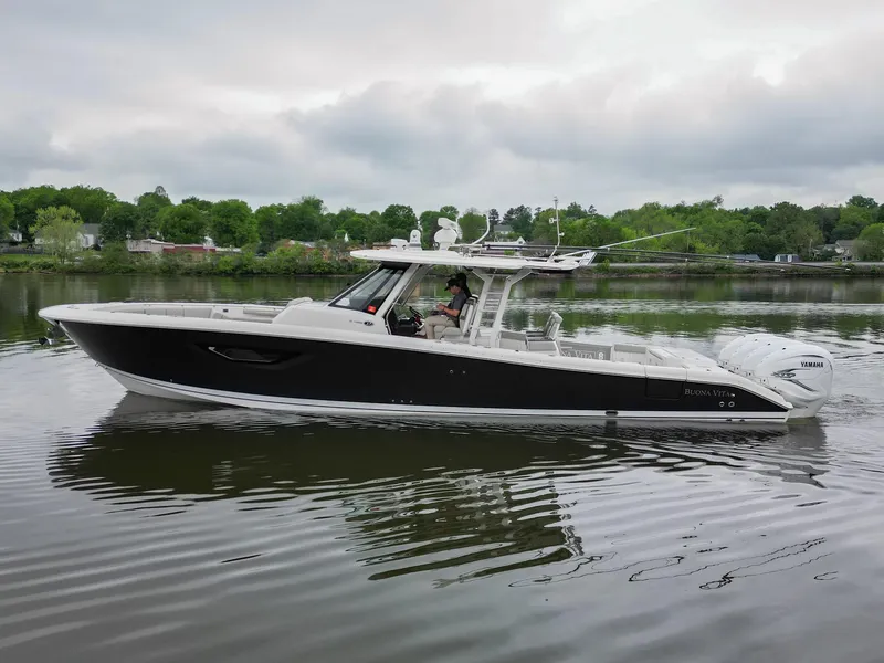 Slide: The Image of 2021 Pursuit S 428 Sport boat cruising on a calm lake with lush green shoreline. - 3