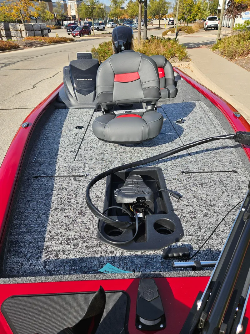 Slide: The Image of 2025 Tracker Pro Team 190 boat with red and gray seating, parked on a street. - 3