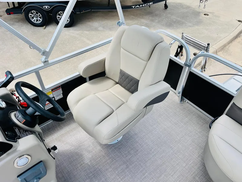 Slide: The Image of 2025 Sun Tracker Party Barge 16 DLX interior with plush captain's chair and steering console. - 26
