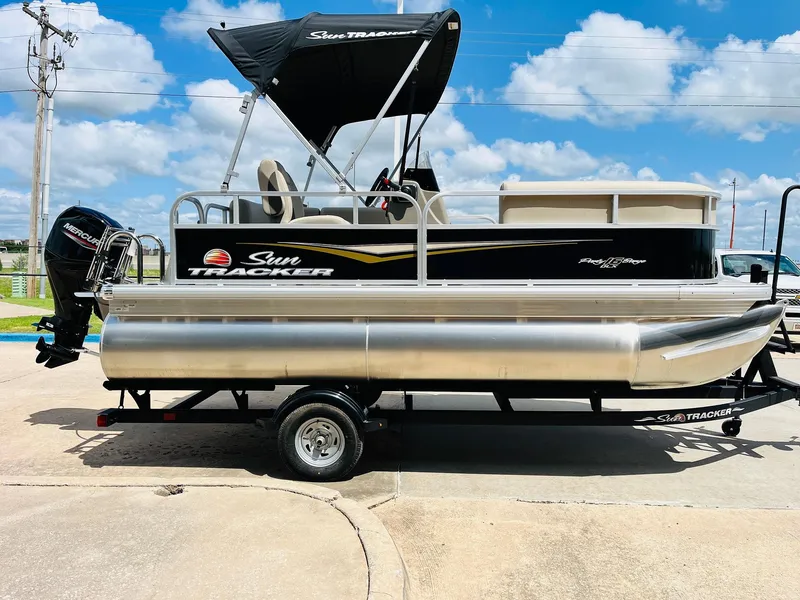 Slide: The Image of 2025 Sun Tracker Party Barge 16 DLX pontoon boat on trailer, under blue sky. - 5