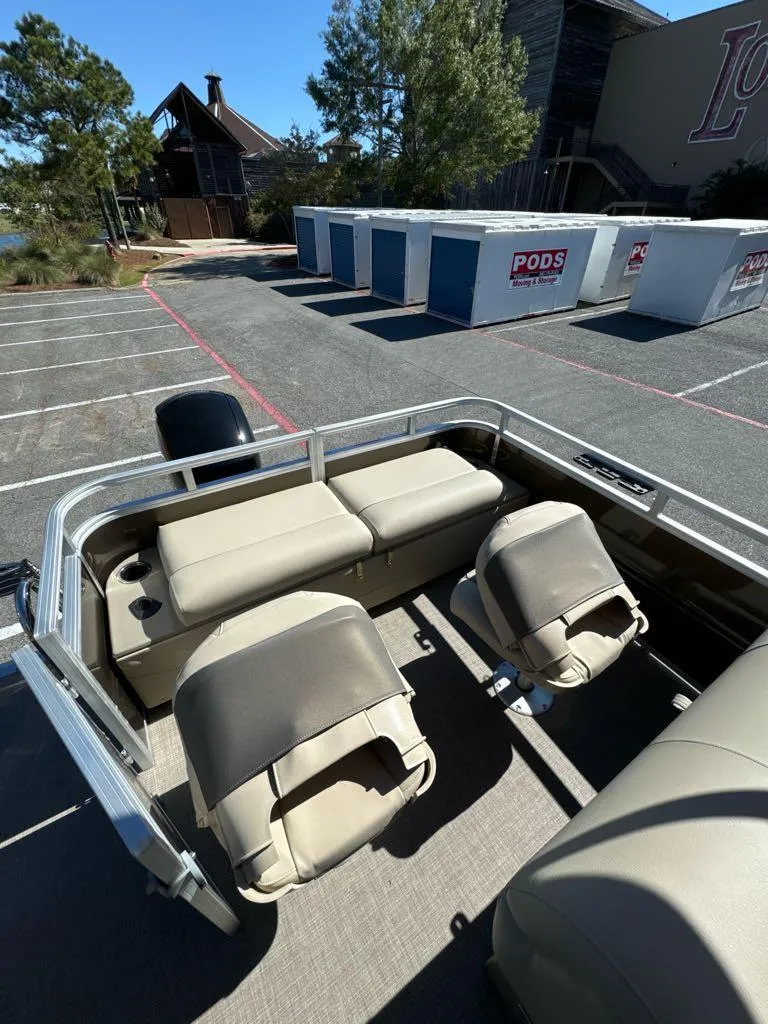 Slide: The Image of 2025 Sun Tracker SportFish 22 XP3 pontoon boat interior with beige seating in a parking lot. - 6