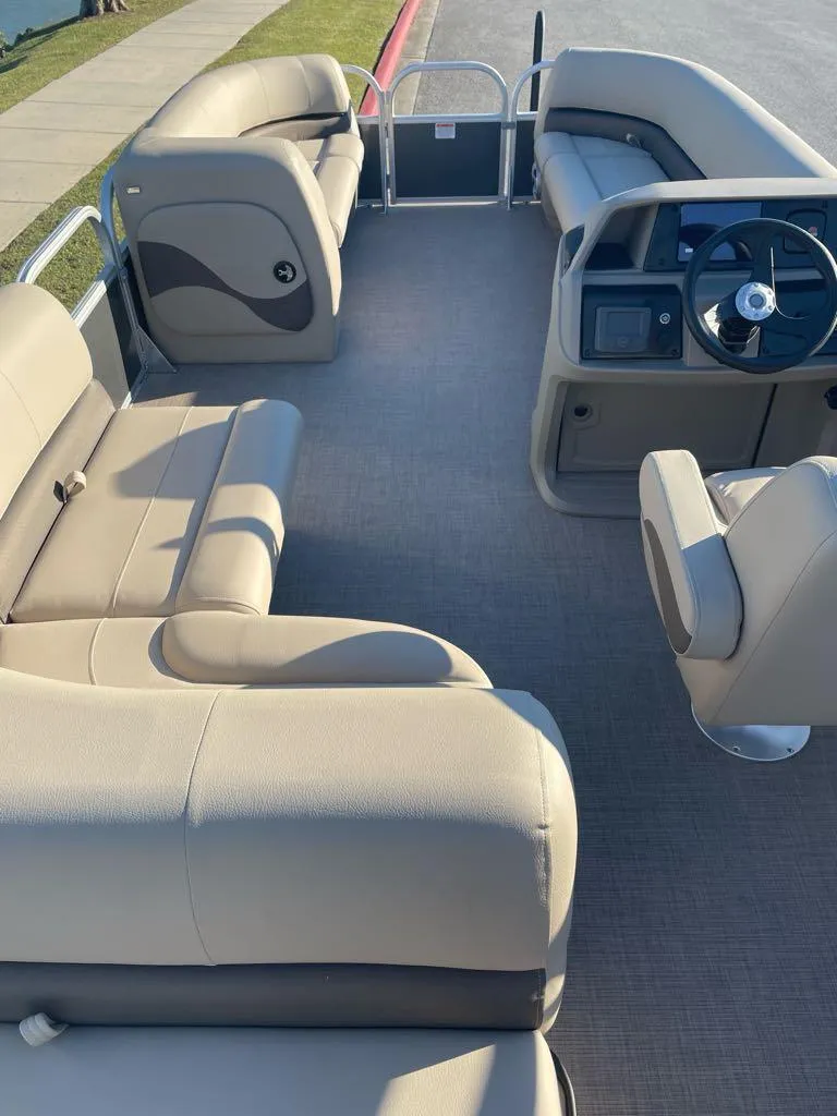 Slide: The Image of 2025 Sun Tracker Party Barge 18 DLX interior with beige seating and steering console. - 3