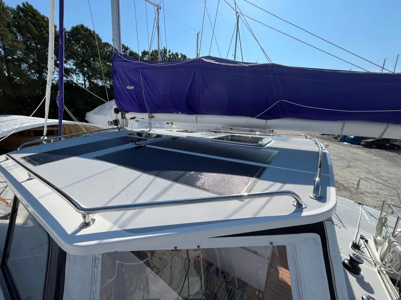 Slide: The Image of 2018 Maine Cat 38 Electric sailboat with purple sail cover, docked under clear blue sky. - 15
