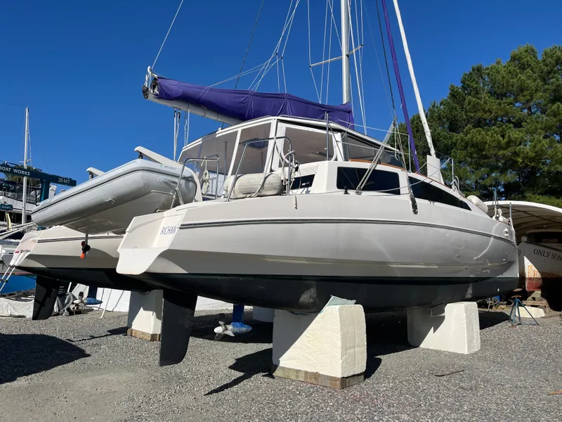 Slide: The Image of 2018 Maine Cat 38 Electric catamaran on stands, with blue sail cover, in a boatyard. - 2