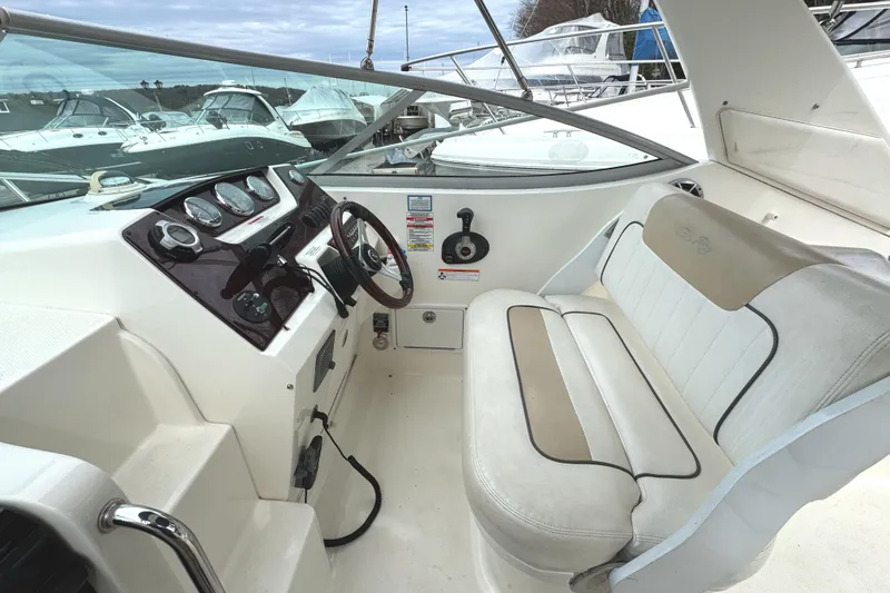 Slide: The Image of 2010 Sea Ray 280 Sundancer cockpit with steering wheel and seating, docked at marina. - 16