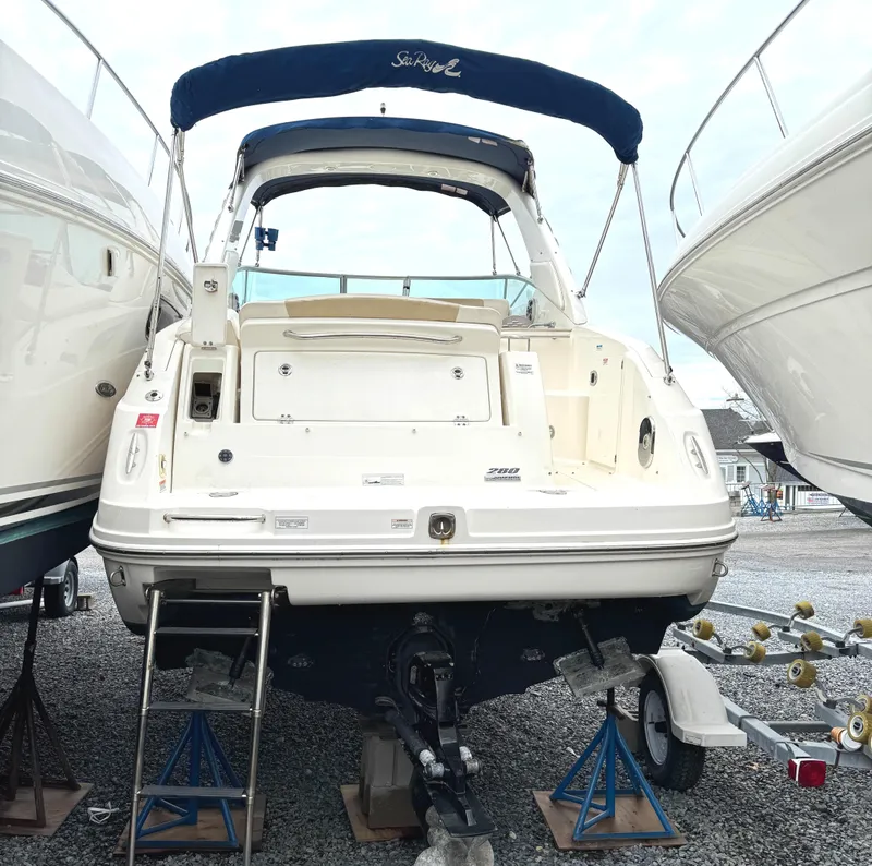 Slide: The Image of 2010 Sea Ray 280 Sundancer boat on stands, rear view, with blue canopy. - 2