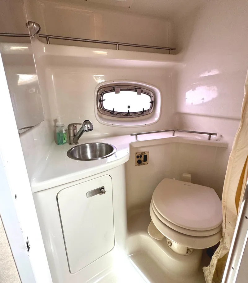 Slide: The Image of 2010 Sea Ray 280 Sundancer bathroom with sink, toilet, and porthole window. - 21