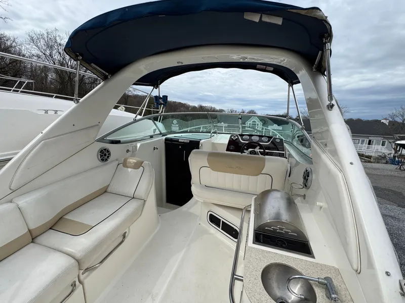 Slide: The Image of 2010 Sea Ray 280 Sundancer boat interior with seating and helm, under a blue canopy. - 7