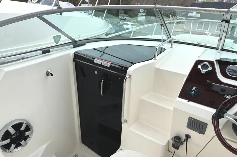 Slide: The Image of 2010 Sea Ray 280 Sundancer cockpit with steering wheel, control panel, and cabin door. - 9