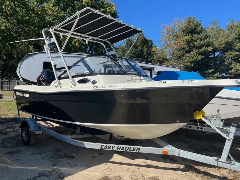 Slide: The Image of 2024 Coastal 198 WT boat on trailer, black and white design, parked outdoors. - 0