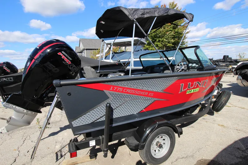 Slide: The Image of 2024 Lund 1775 Crossover XS boat with canopy on trailer, outdoors. - 1