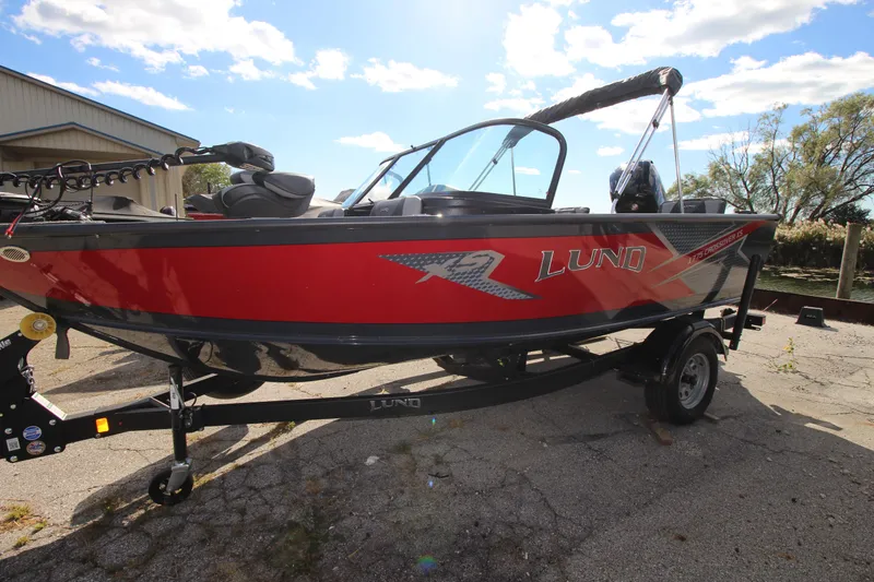 Slide: The Image of 2024 Lund 1775 Crossover XS boat on trailer, red and black design, outdoor setting. - 15