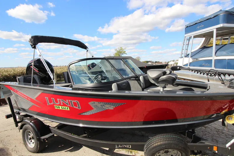 Slide: The Image of 2024 Lund 1775 Crossover XS boat for sale, red exterior, parked outdoors. - 2