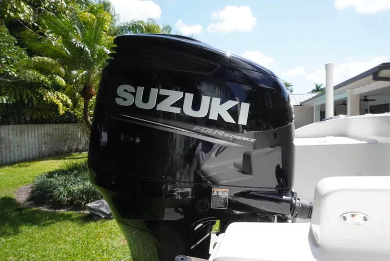 Slide: The Image of Suzuki outboard motor on 2021 Sea Pro 219 boat, sunny day, lush greenery. - 11