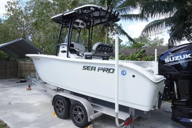 Slide: The Image of 2021 Sea Pro 219 boat on trailer with Suzuki outboard motor, parked outdoors. - 2