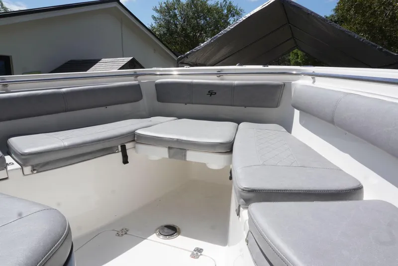 Slide: The Image of 2021 Sea Pro 219 boat interior with cushioned seating in a sunny setting. - 24