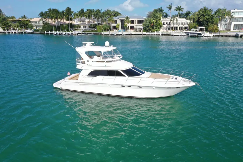Slide: The Image of 2001 Sea Ray 480 Sedan Bridge yacht on turquoise water near luxury waterfront homes. - 12
