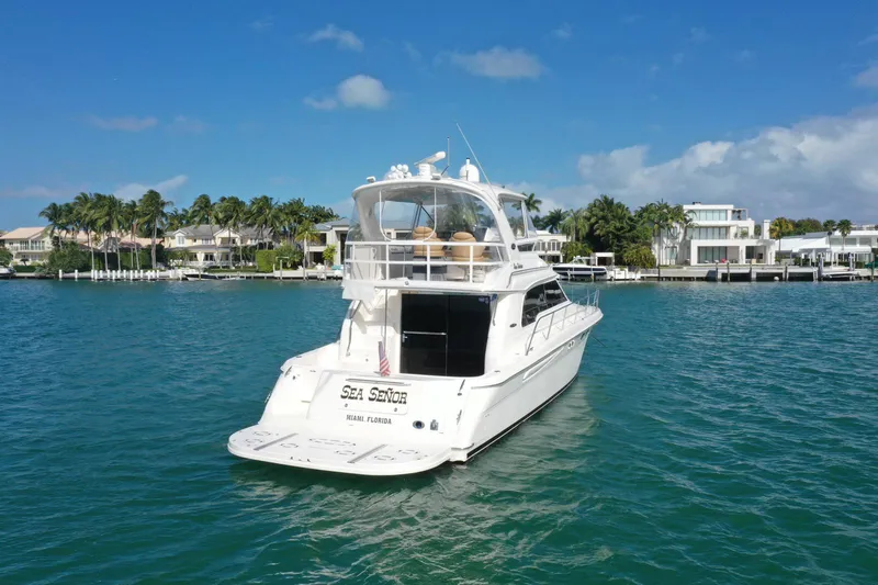 Slide: The Image of 2001 Sea Ray 480 Sedan Bridge yacht on clear blue water, near luxury waterfront homes. - 23