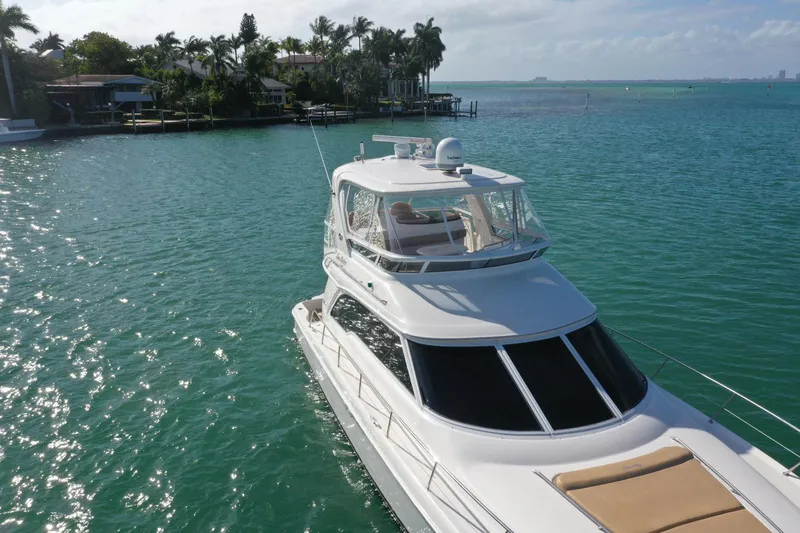 Slide: The Image of 2001 Sea Ray 480 Sedan Bridge yacht cruising in turquoise waters near a tropical shoreline. - 28