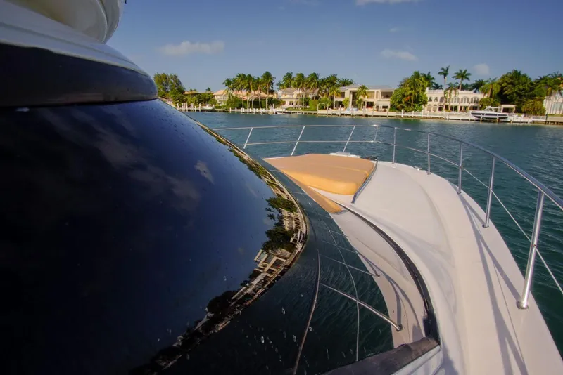 Slide: The Image of 2001 Sea Ray 480 Sedan Bridge yacht on serene water with luxury homes in background. - 37