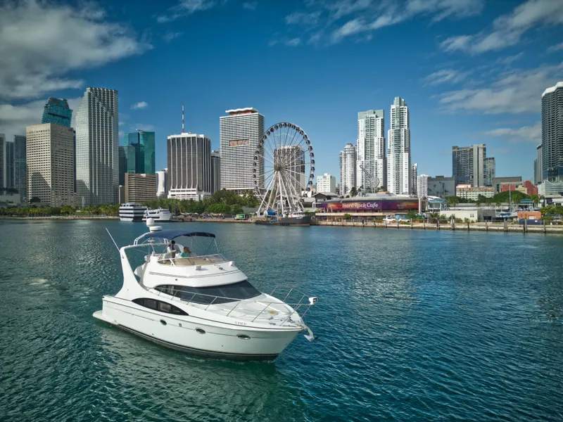Slide: The Image of 2002 Carver 410 Sport Sedan yacht cruising near a city skyline with a Ferris wheel. - 2