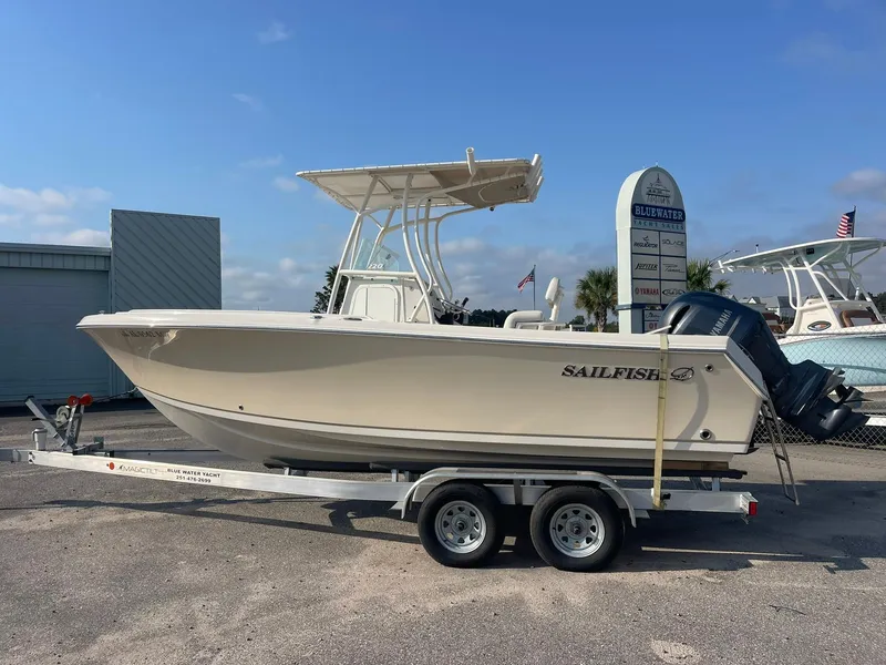 Slide: The Image of 2016 Sailfish 220 CC boat on trailer, parked outdoors under clear sky. - 0