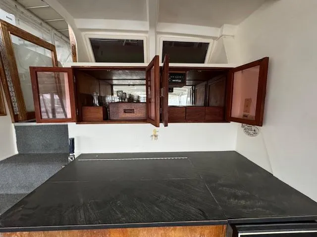 Slide: The Image of 1987 Seamaster 48 Motor Yacht interior with open wooden cabinets and black countertop. - 24
