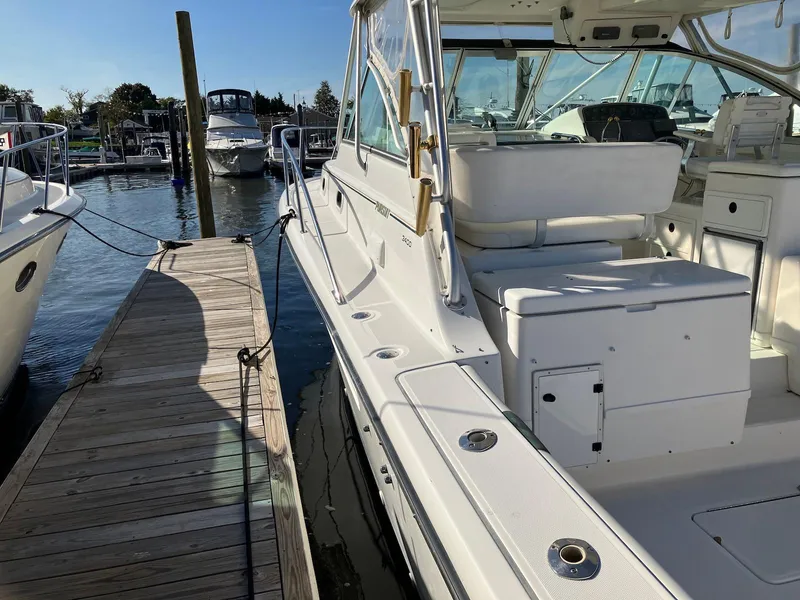 Slide: The Image of 2000 Pursuit 3400 Express boat docked at marina, showcasing spacious deck and seating area. - 6