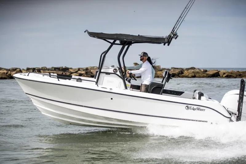 Slide: The Image of 2025 Edgewater 208CC Watchman boat cruising on water near rocky shoreline. - 10