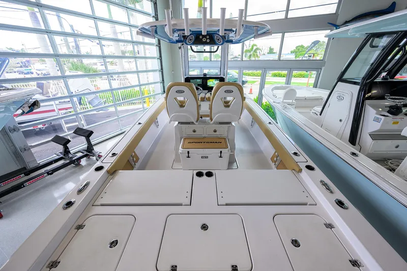 Slide: The Image of 2025 Sportsman Masters 267 Bay Boat interior, showcasing seating and storage in a showroom setting. - 21
