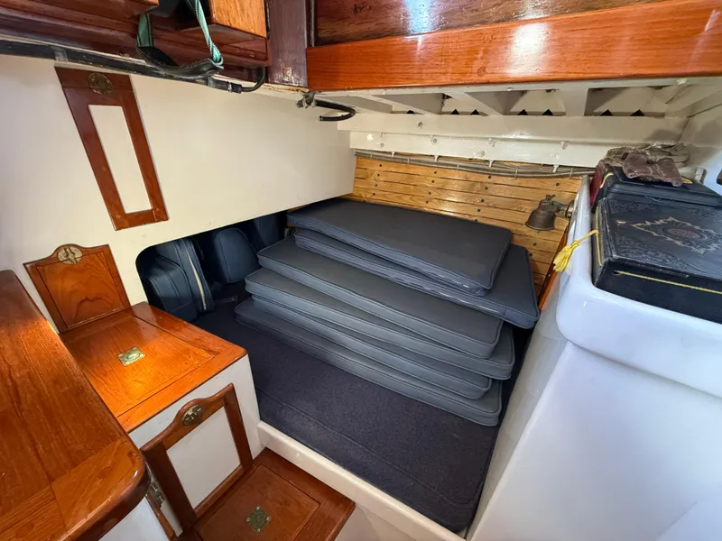 Slide: The Image of Interior of 1932 Historic Fellows & Stewart Yawl with stacked cushions and wooden cabinetry. - 15