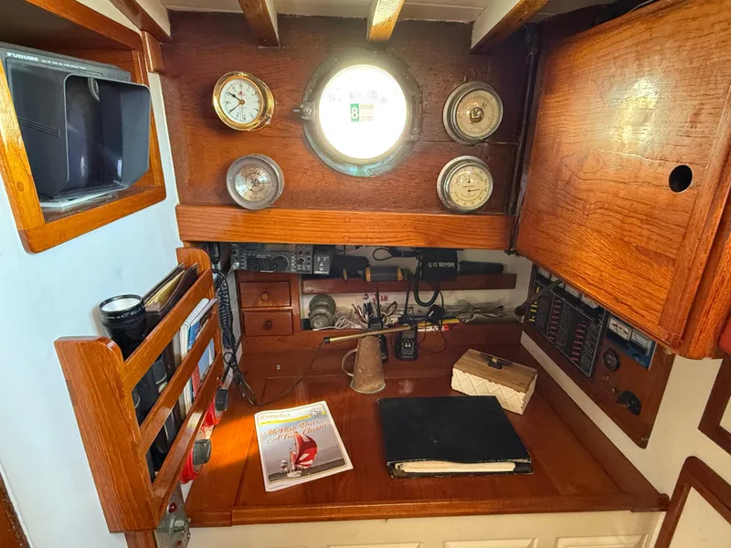 Slide: The Image of Interior of 1932 Fellows & Stewart Yawl with wooden desk, nautical instruments, and porthole. - 16