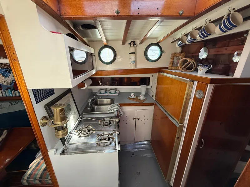 Slide: The Image of Interior of a 1932 Historic Fellows & Stewart Yawl, featuring a classic wooden galley kitchen. - 24