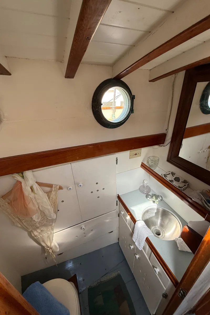 Slide: The Image of Interior of 1932 Fellows & Stewart Yawl, featuring a compact bathroom with porthole and wooden accents. - 27